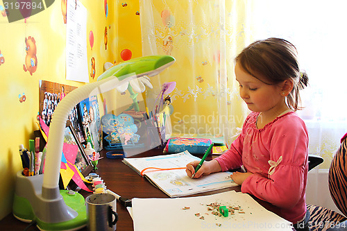 Image of girl the schoolgirl learns lessons at the table