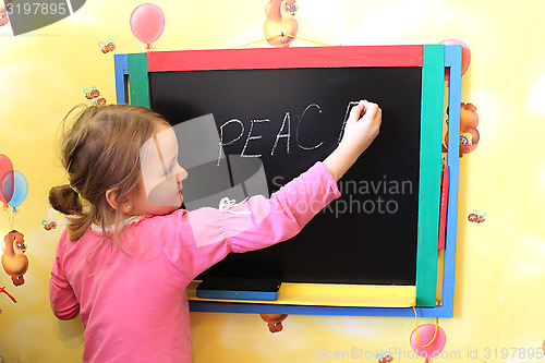 Image of girl writes on blackboard word the peace