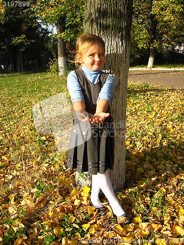 Image of little girl with yellow leaf in autumn