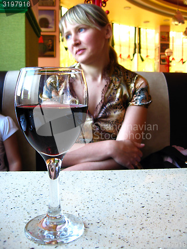 Image of glass of red wine on the table and a girl