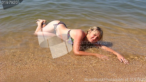 Image of girl laying on sand at the seacoast