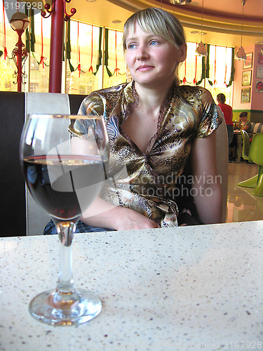 Image of glass of red wine on the table and a girl