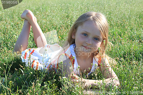 Image of portrait of little girl lying on the grass