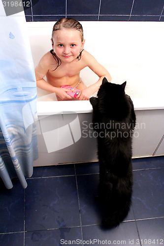 Image of little girl taking a bath with curious black cat