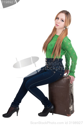 Image of Attractive red-haired woman on old suitcase