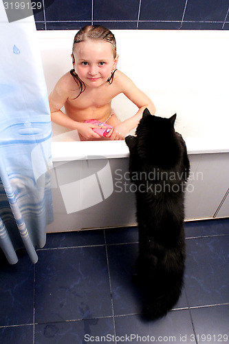 Image of little girl taking a bath with curious black cat