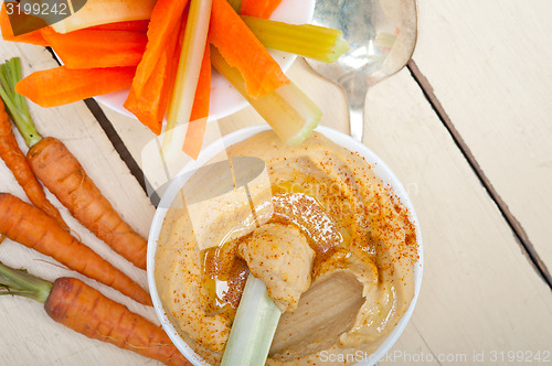 Image of fresh hummus dip with raw carrot and celery 
