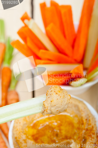 Image of fresh hummus dip with raw carrot and celery 