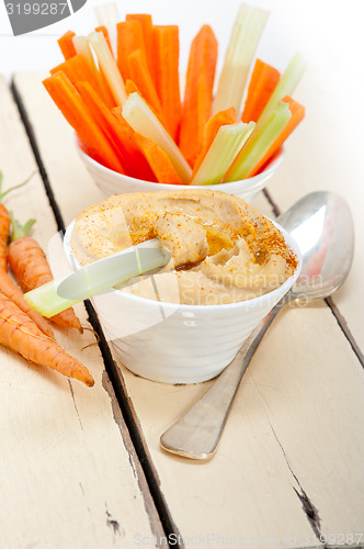 Image of fresh hummus dip with raw carrot and celery 