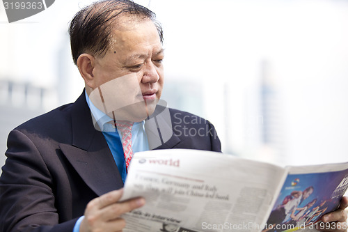 Image of Asian businessman reading newspaper