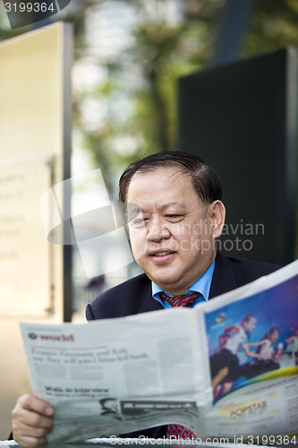 Image of Asian businessman reading newspaper