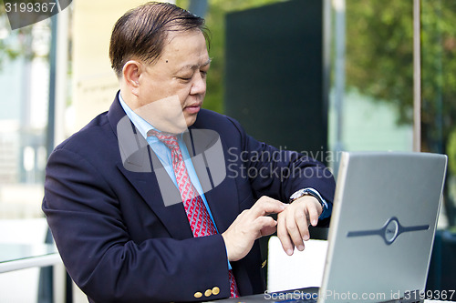 Image of Asian businessman looking at watch