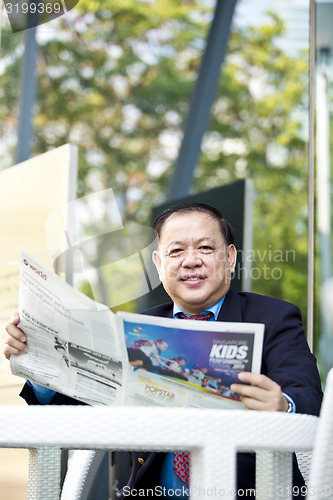 Image of Asian businessman reading newspaper