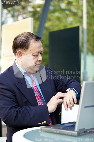 Image of Asian businessman looking at watch