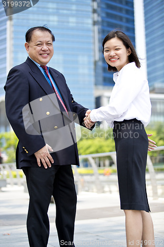 Image of Asian businessman and young female executive shaking hands