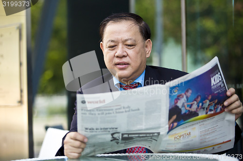 Image of Asian businessman reading newspaper