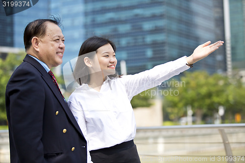 Image of Asian businessman and young female executive pointing at a direction