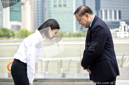 Image of Asian businessman and young female executive bowing