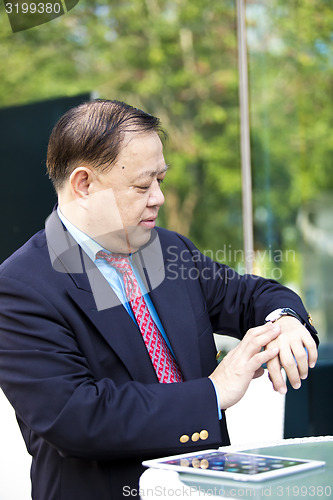 Image of Asian businessman looking at watch