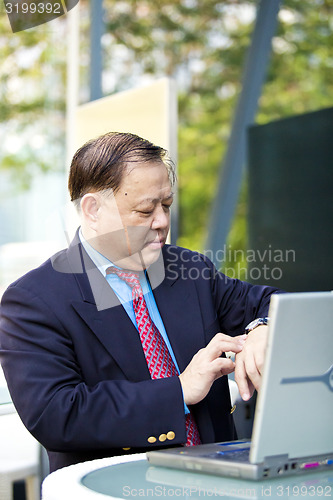 Image of Asian businessman looking at watch