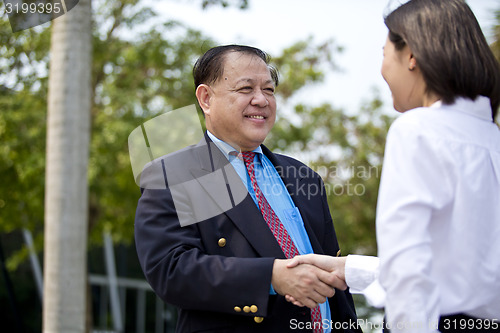 Image of Asian businessman and young female executive shaking hands