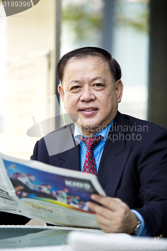 Image of Asian businessman reading newspaper