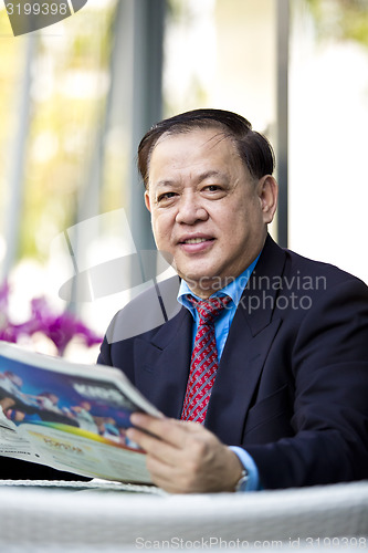 Image of Asian businessman reading newspaper