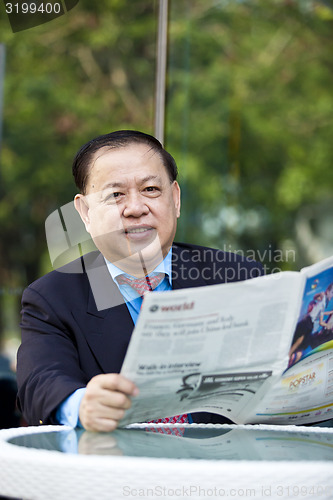 Image of Asian businessman reading newspaper