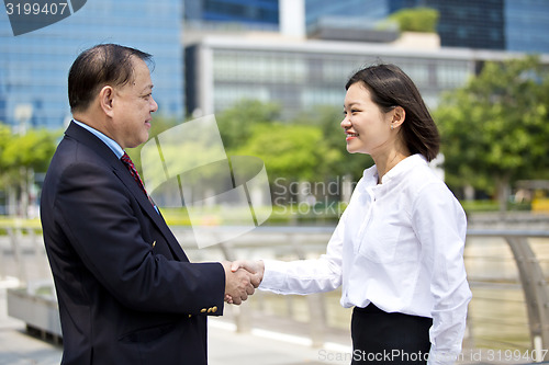 Image of Asian businessman and young female executive shaking hands