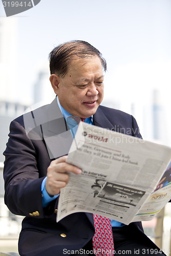 Image of Asian businessman reading newspaper