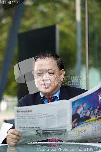 Image of Asian businessman reading newspaper