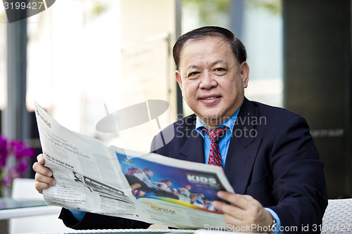 Image of Asian businessman reading newspaper