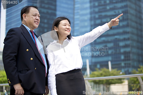 Image of Asian businessman and young female executive pointing at a direction