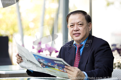 Image of Asian businessman reading newspaper