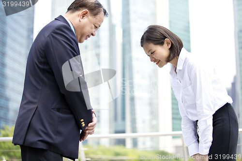 Image of Asian businessman and young female executive bowing