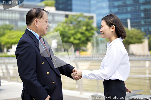 Image of Asian businessman and young female executive shaking hands