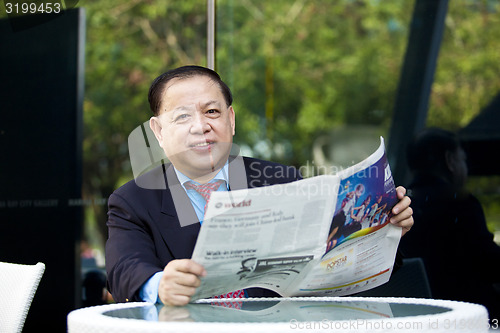 Image of Asian businessman reading newspaper