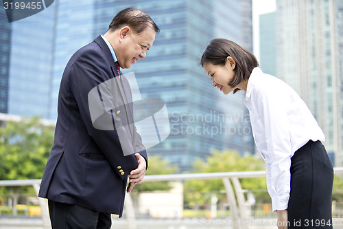 Image of Asian businessman and young female executive bowing