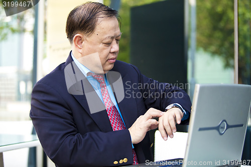 Image of Asian businessman looking at watch