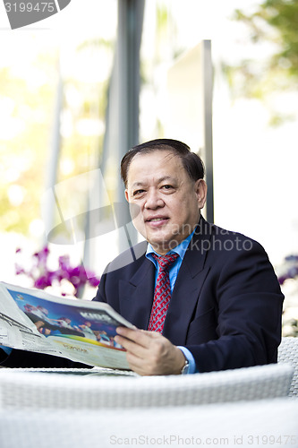 Image of Asian businessman reading newspaper