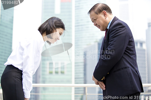 Image of Asian businessman & young female executive bowing