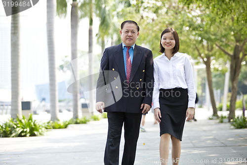 Image of Asian businessman & young female executive walking