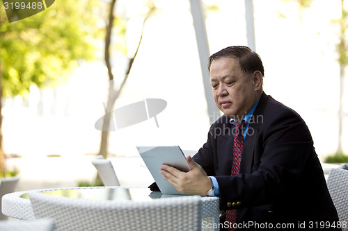 Image of Asian businessman using tablet