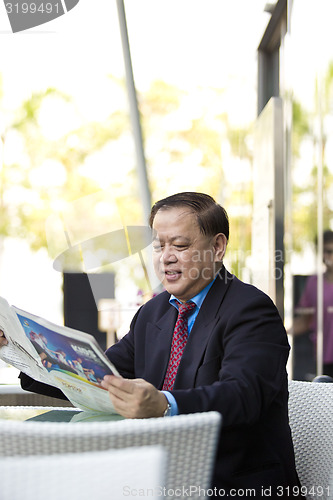 Image of Asian businessman reading newspaper