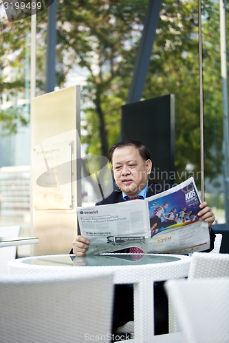 Image of Asian businessman reading newspaper