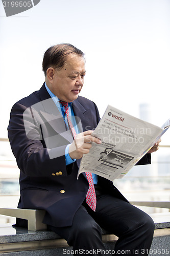 Image of Asian businessman reading newspaper