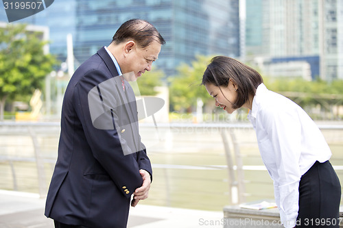 Image of Asian businessman & young female executive bowing