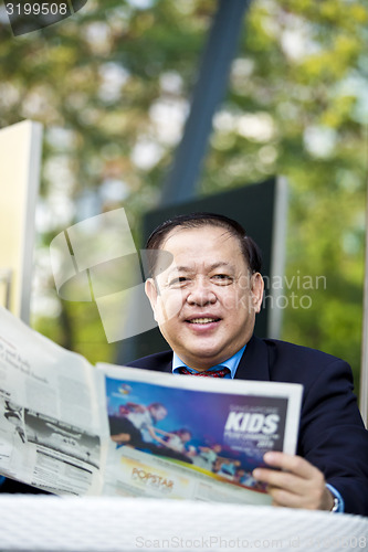 Image of Asian businessman reading newspaper