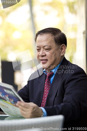 Image of Asian businessman reading newspaper