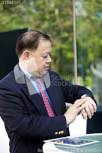 Image of Asian businessman looking at watch